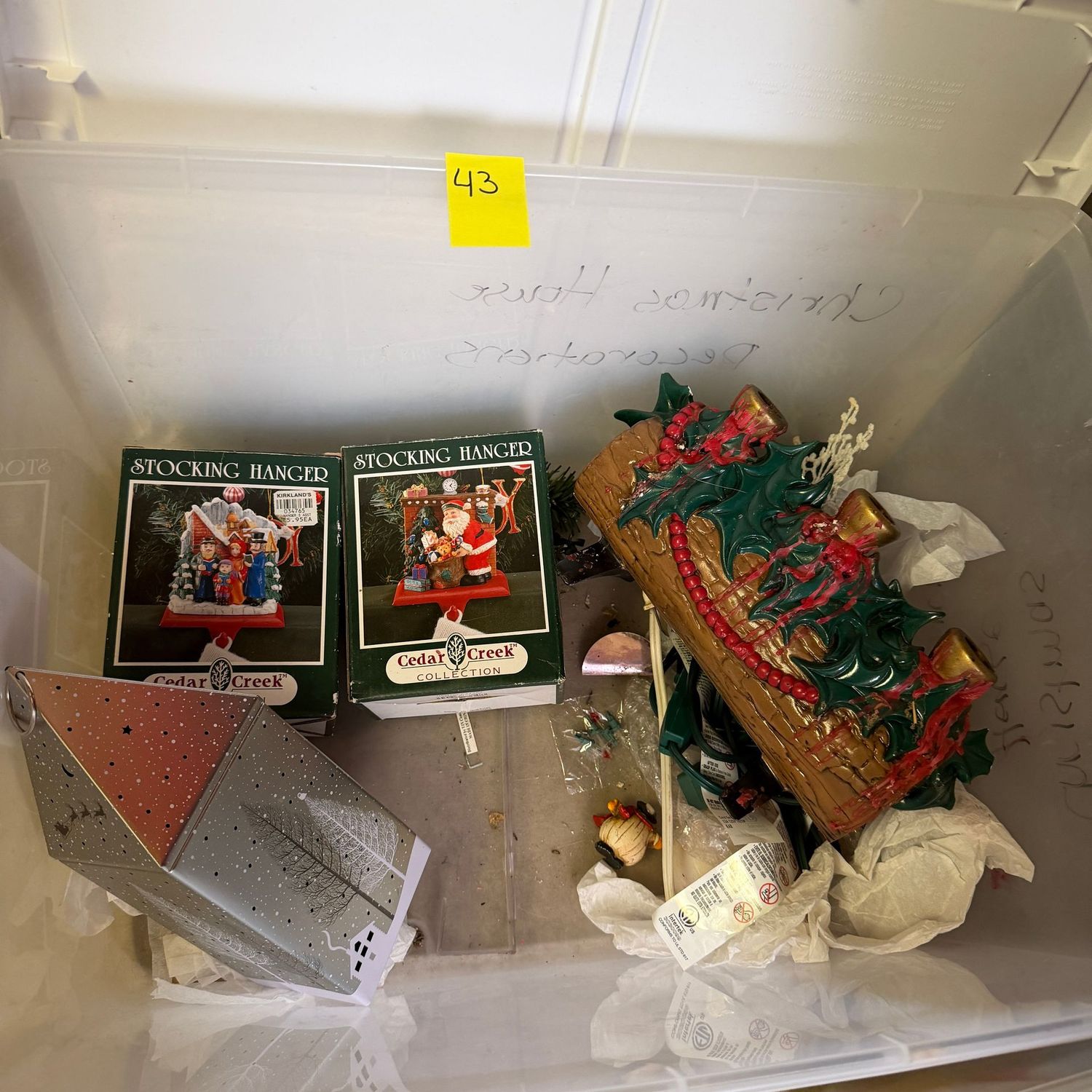 Lot #43, bin of Christmas decorations, luminary, stocking hanger, ceramic yule log Lot #43, bin of Christmas decorations, luminary, stocking hanger, ceramic yule log