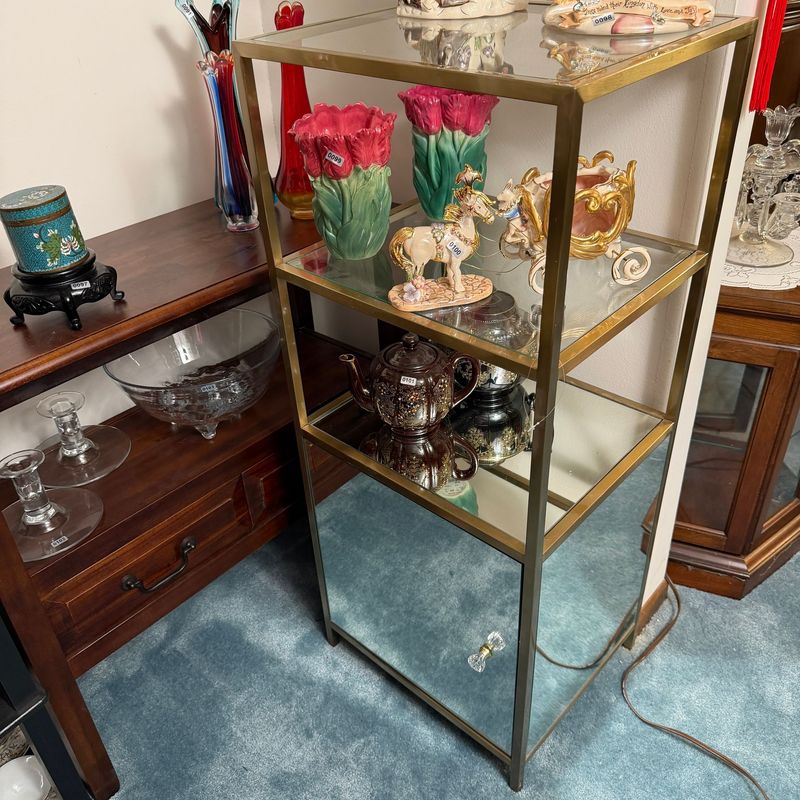 Metal stand with brass finish, clear glass shelves, and mirrored lower storage, 39"H x 14"D x 16"W