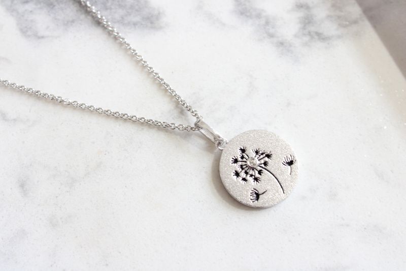Sterling silver engraved with a dandelion motif and accented by a single sparking white topaz.