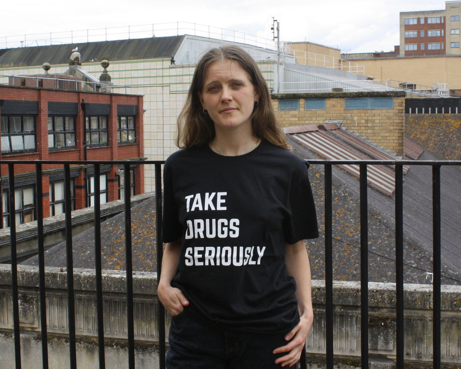 Ester is wearing a short-sleeved black t-shirt with ‘Take drugs seriously’ printed in white across the front.