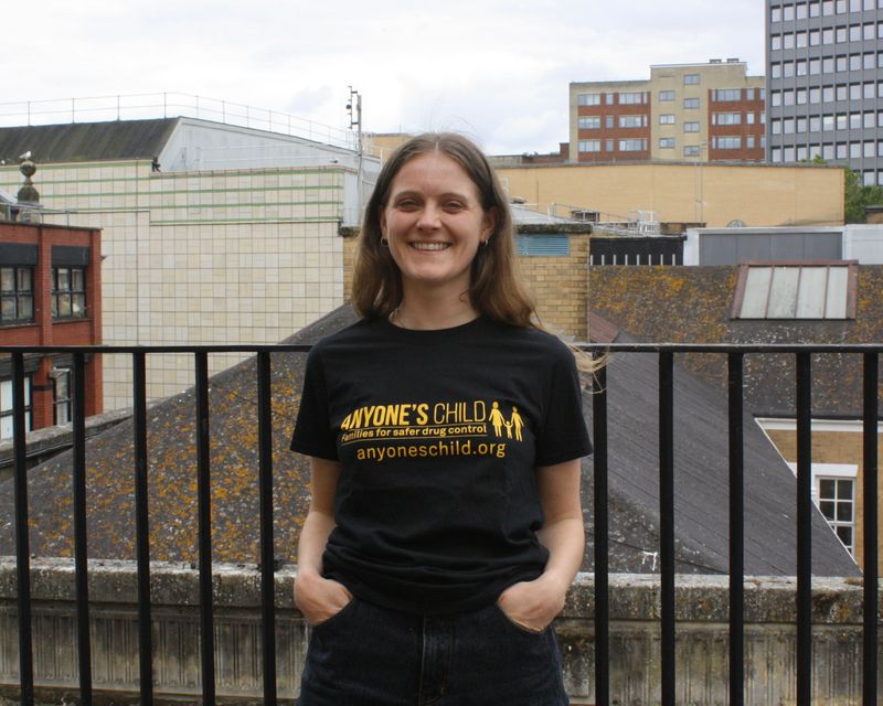 Ester is wearing a short-sleeved black t-shirt with &#39;Anyone&#39;s Child Families for Safer Drug Control&#39; printed in yellow across the chest.