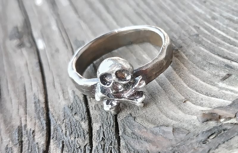 Anello con teschio e ossa incrociate, in bronzo o argento. 