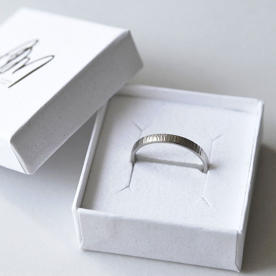 Alliance martelée en or gris 18K présentée dans son écrin blanc.