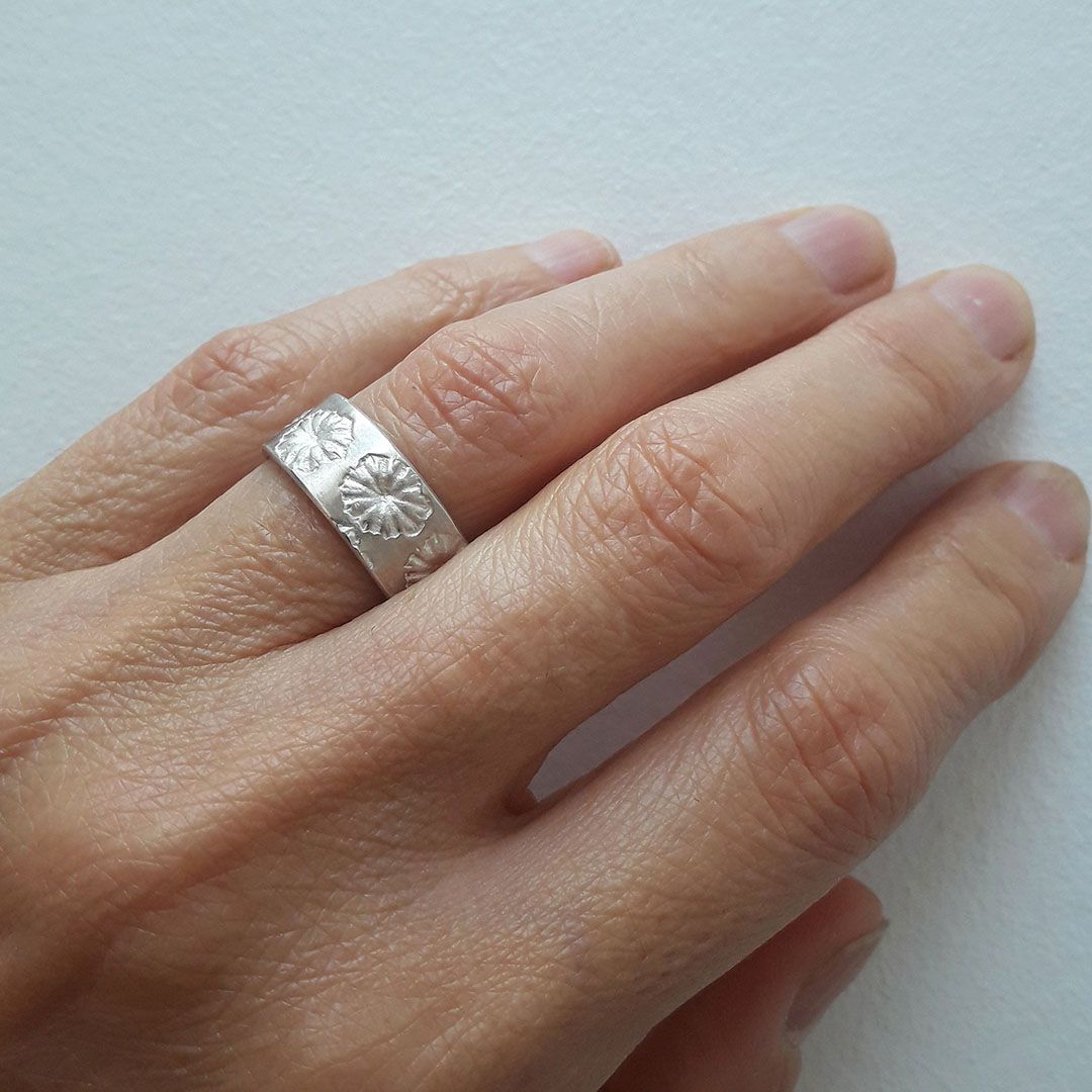 Anneau Pavots en argent 925 largeur 7 mm porté majeur main gauche.