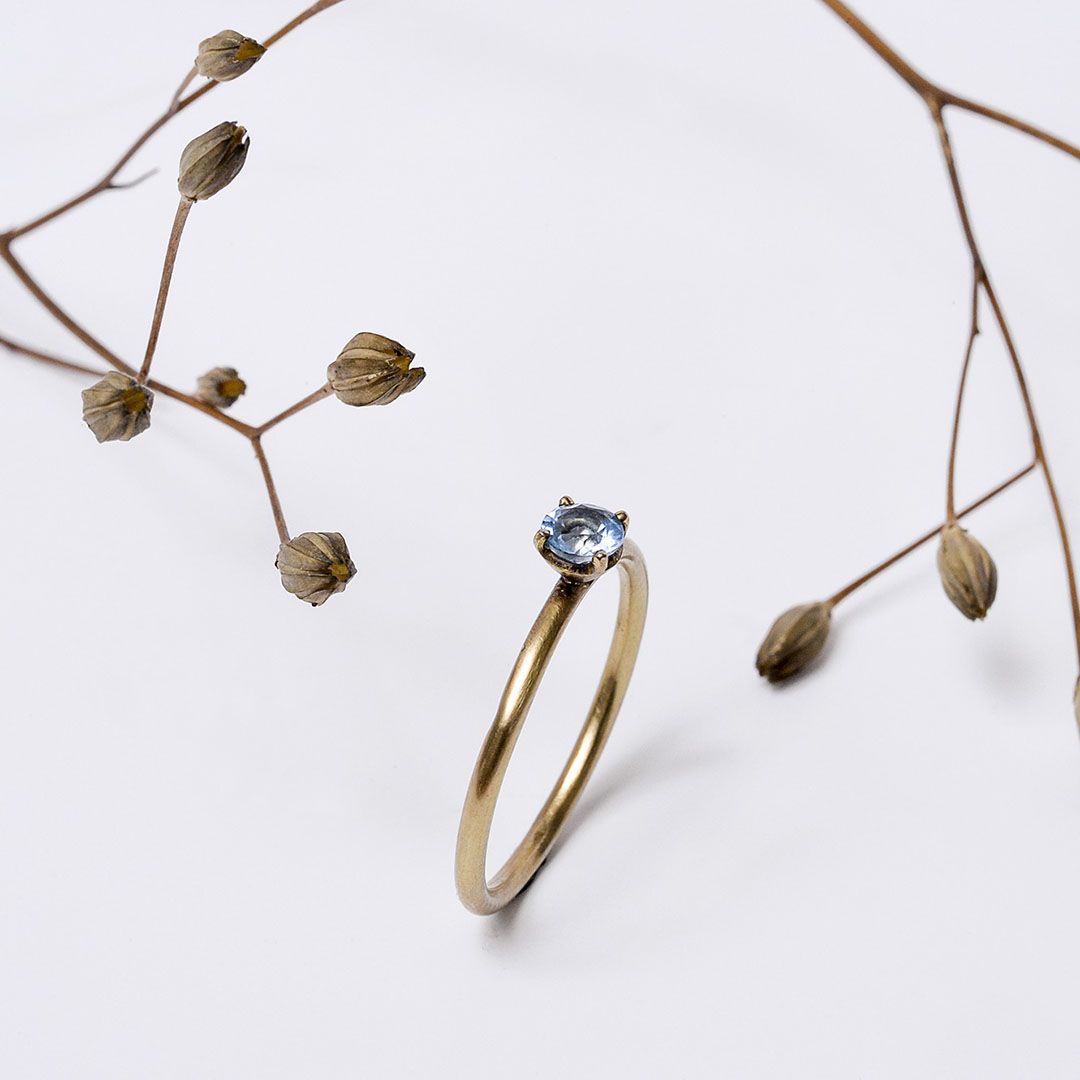 Bague en or jaune et topaze bleue, bague de demande en mariage. présentée avec des végétaux