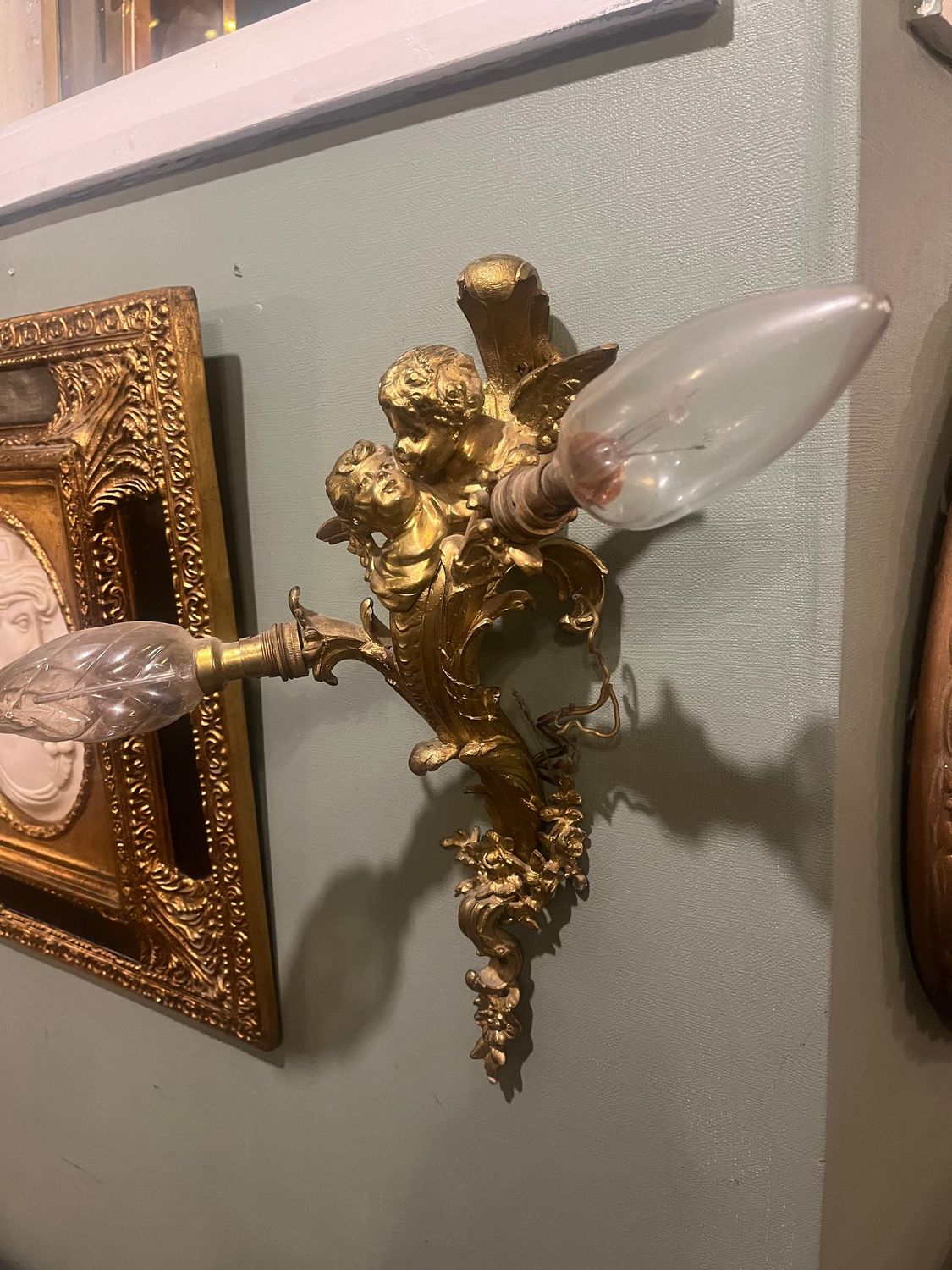 Pair of Early 20th Century French Gilt Brass Cherub Wall Lights Ornate French gilt brass wall light showing twin branches, cherubs and scrolling floral decoration