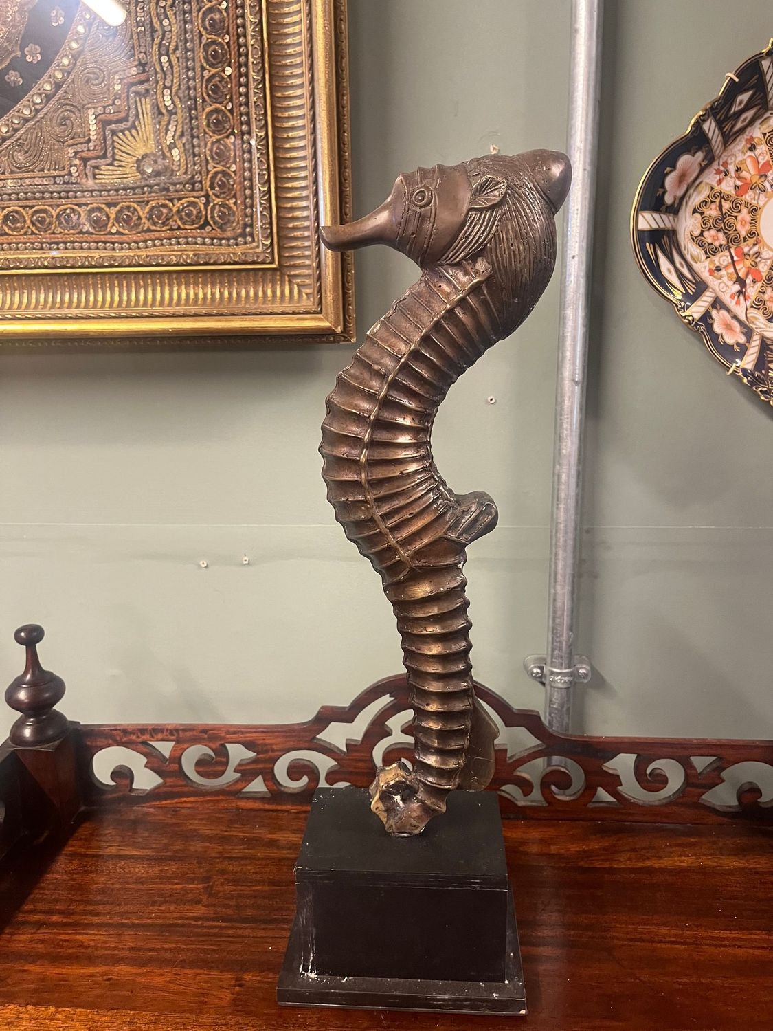 Large Cast Metal Seahorse Sculpture on Black Plinth Tall bronze-toned seahorse sculpture with a curved ridged body on a black plinth
