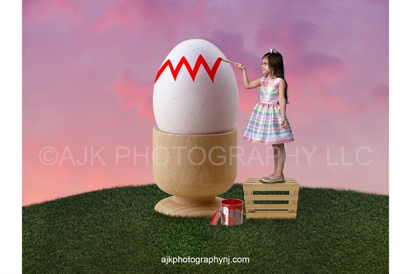 Painting a giant Easter egg on a grass hill, pink sky, Easter digital backdrop