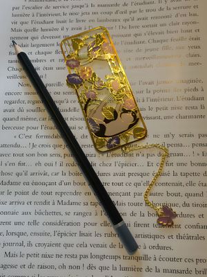 marque-page en métal avec un chat autour de fleurs, une chaine dorée et un papillon violet