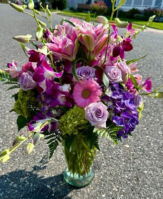 Elegant coastal-inspired floral design with purple hydrangeas, double-bloom lilies, roses, and textured greenery