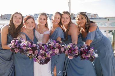 A bride and her bridesmaids carry purple bouquets made by Coventry Crossing Florist in Stone Harbor, NJ