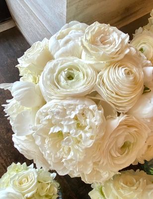 A beautiful white wedding bouquet featuring peonies, ranunculus and roses, made by Coventry Crossing Florist in Stone Harbor 