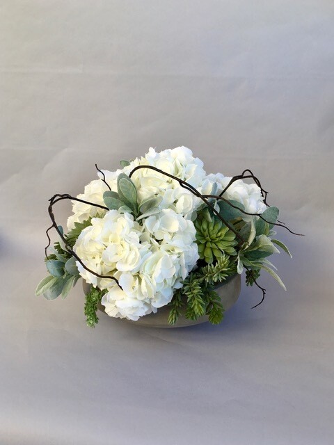 White hydrangeas and mixed succulents in a concrete bowl