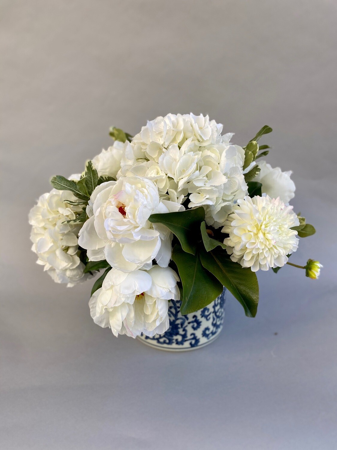 White hydrangeas and peonies in a blue and white vase
