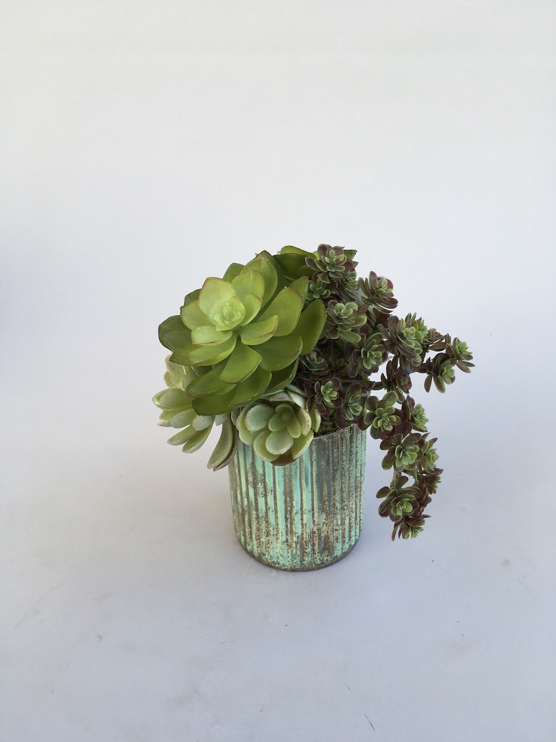 Echeveria, agave and sedum succulents in a patina mercury vase