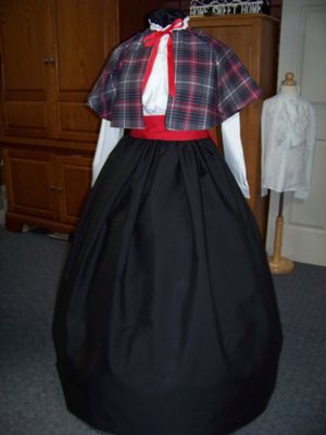 Dicken's Christmas Caroler cape Red and black and gray Plaid flannel cape reversible with black on back one size fits most with Black Skirt and red sash. Handmade in USA