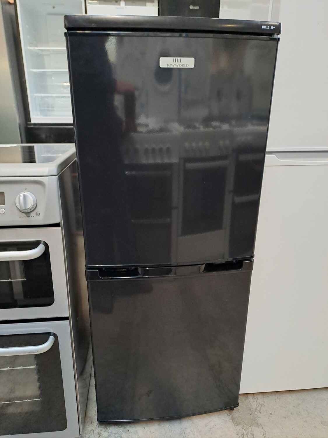 New World NWCOM5012 Fridge Freezer Black - H124 x W50 X D55  Brand New Graded 12 Month Guarantee. This item is located in our Whitby Road Shop 