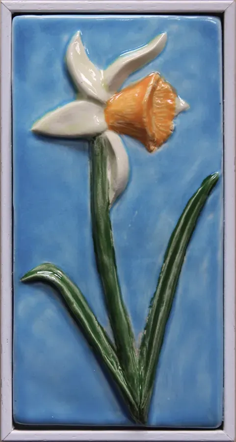 framed white framed sky blue tile featuring an orange trumpeted daffodil
