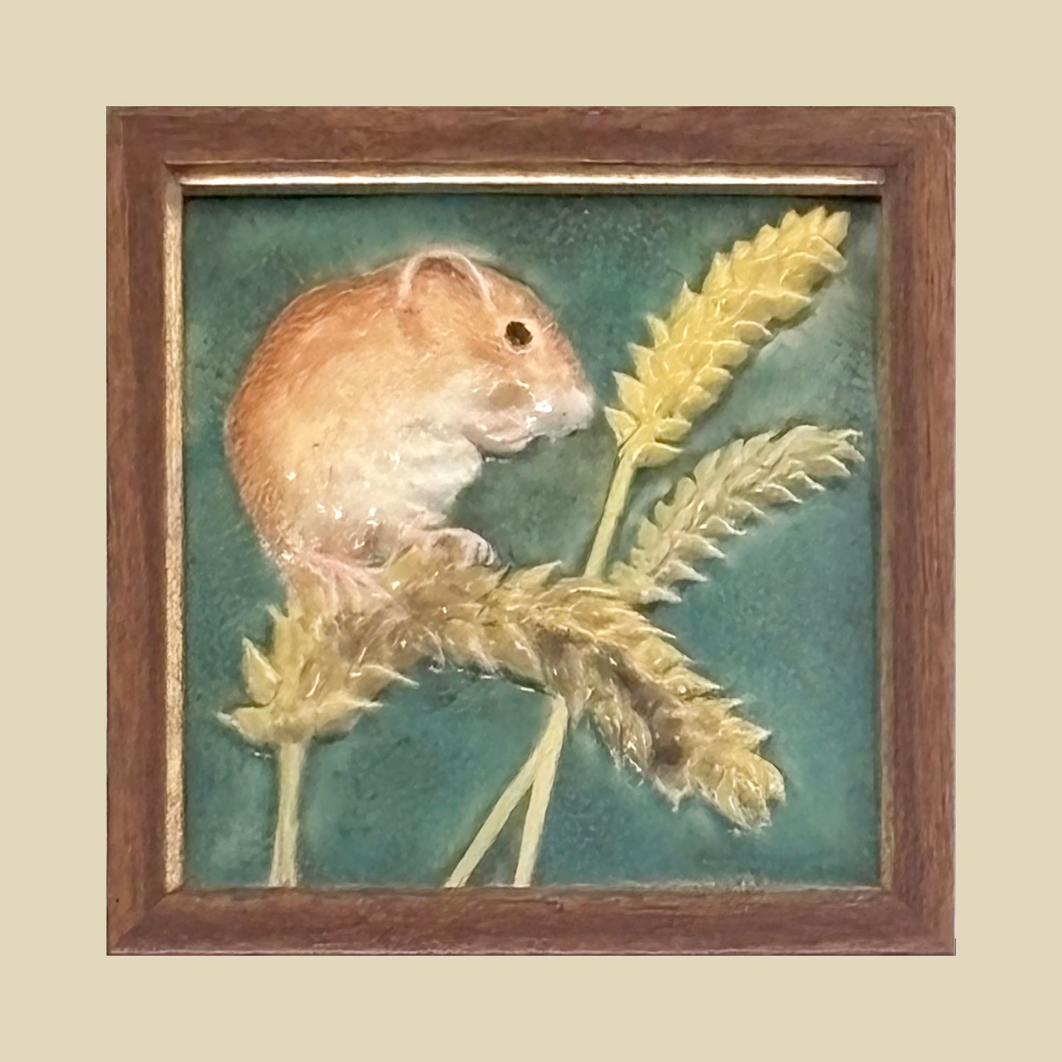 ​A ceramic tile depicting a field mouse eating on a ripe wheat head