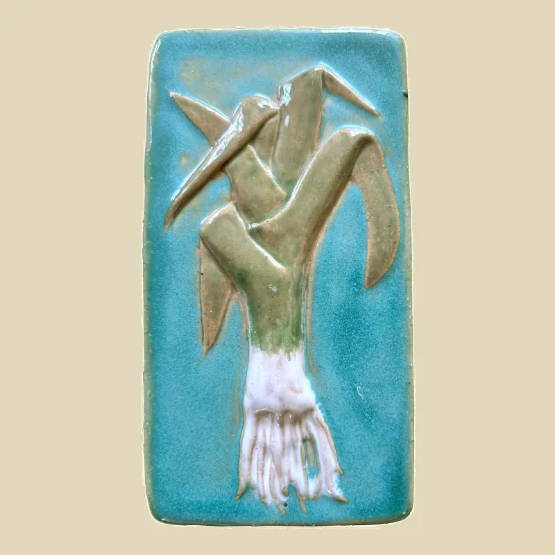 This is a framed ceramic feature tile titled "Leek" It is hand painted in turquoise and green glazes