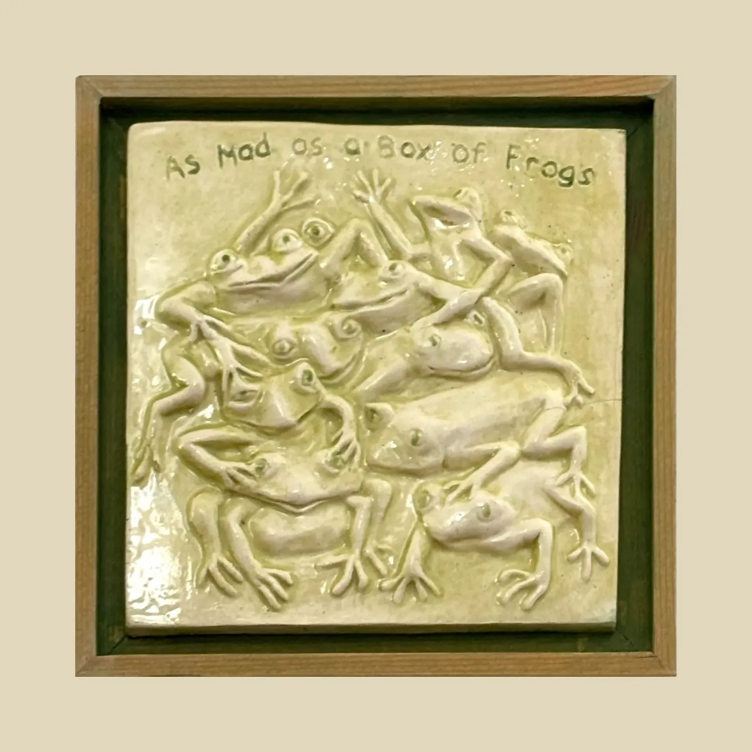 A stunning framed 13cm x 13cm ceramic feature tile depicting a heap of scrambling frogs