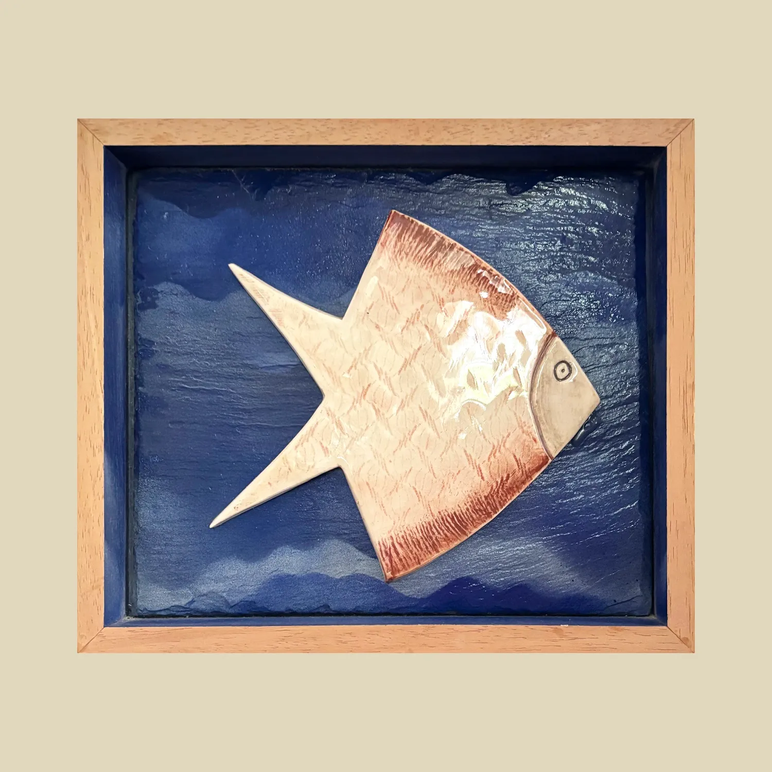 A stylised 16cm x 16cm fish tile set on a 23.5cm x 20cm blue painted slate background in a wood box frame.