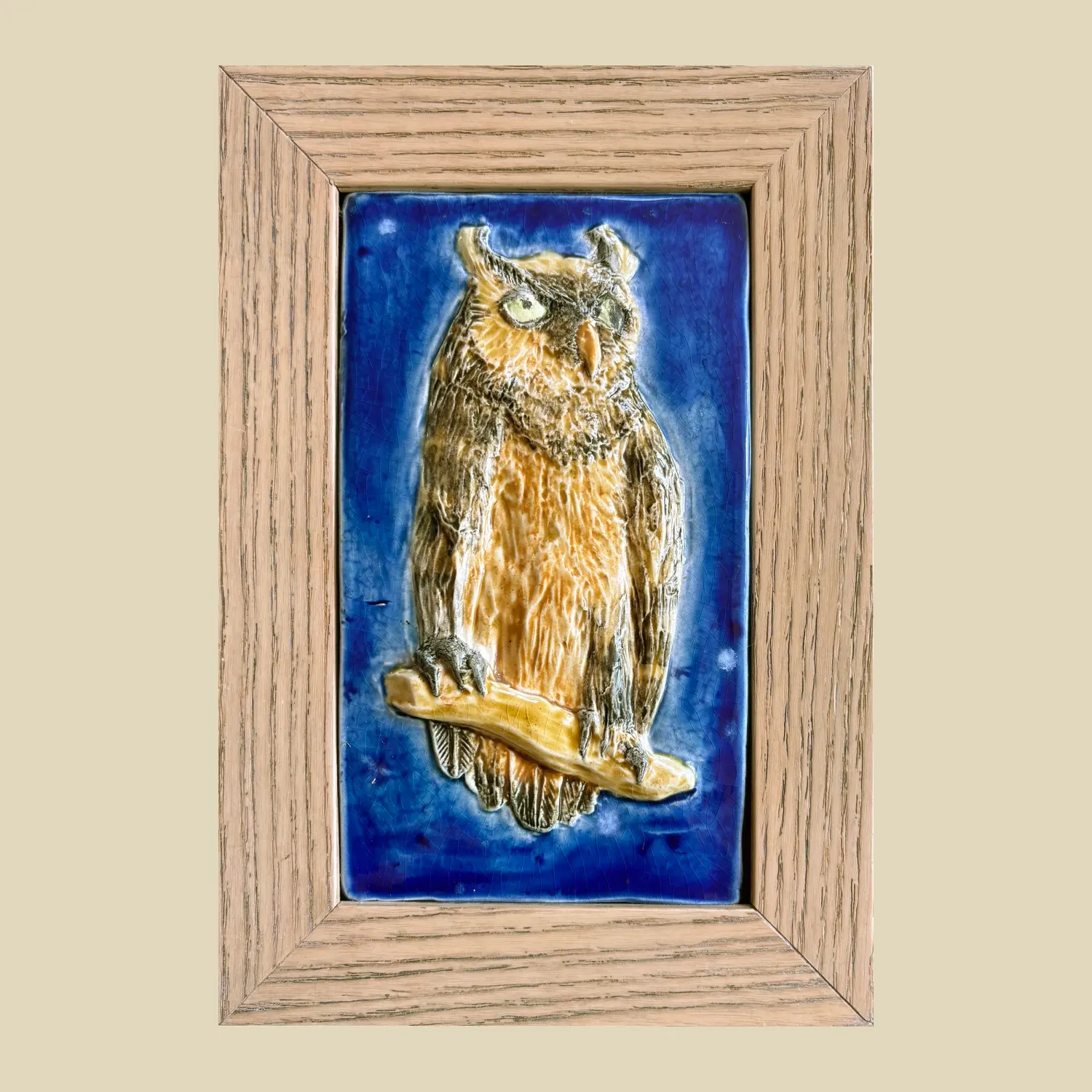 A framed 9.5cm x 16cm ceramic feature tile depicting a long eared owl perched on a branch