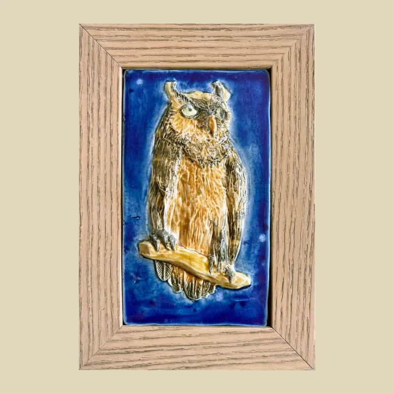 A framed 9.5cm x 16cm ceramic feature tile depicting a long eared owl perched on a branch