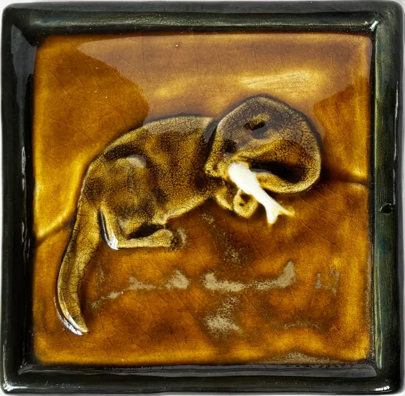 A  feature tile of a cute otter busily eating a fish on a rock beside a river. 12.5cms x 12.5cms or 4.75" x 4.75"