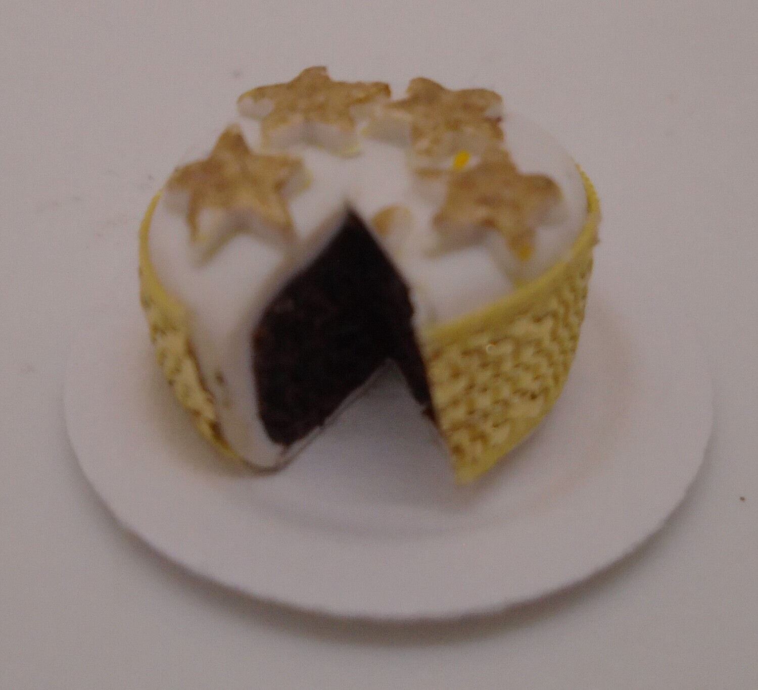 CHRISTMAS CAKE WITH GOLD STARS AND RIBBON WITH SLICE OUT