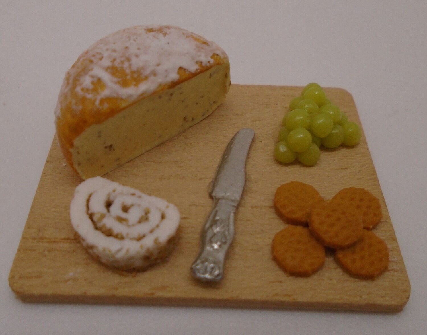 CHEESE BOARD WITH CRACKERS KNIFE AND GRAPES