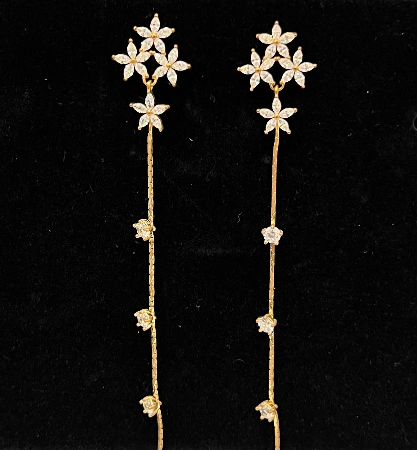 Aretes dorados de flores con linea de cristares