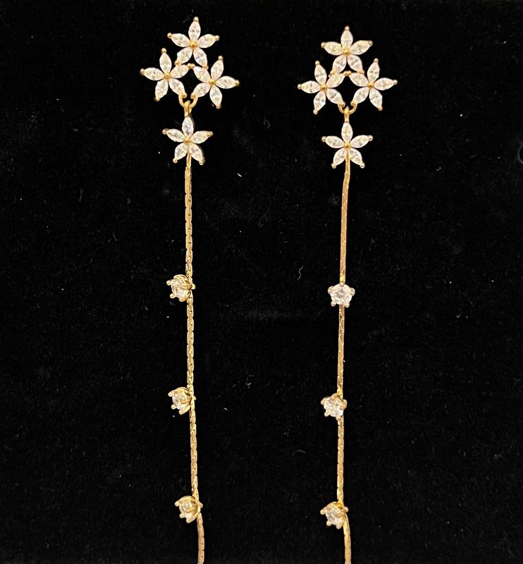 Aretes dorados de flores con linea de cristares