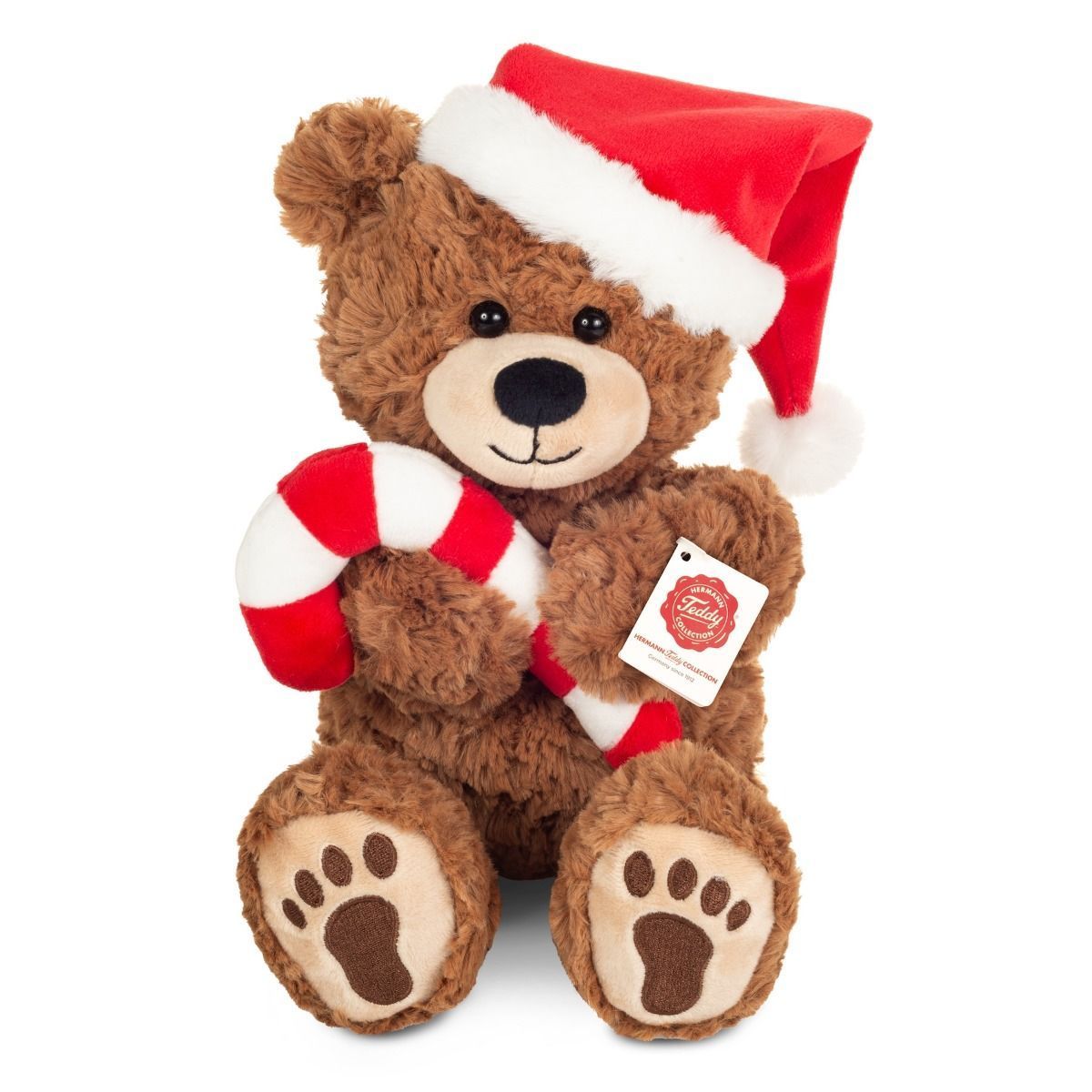 Weihnachtsteddy mit Zuckerstange - Hermann Teddy Hermann Teddy Weihnachtsteddy sitzend aus honiggoldenem Plüsch mit roter Mütze und gestreifter Zuckerstange in den Pfoten