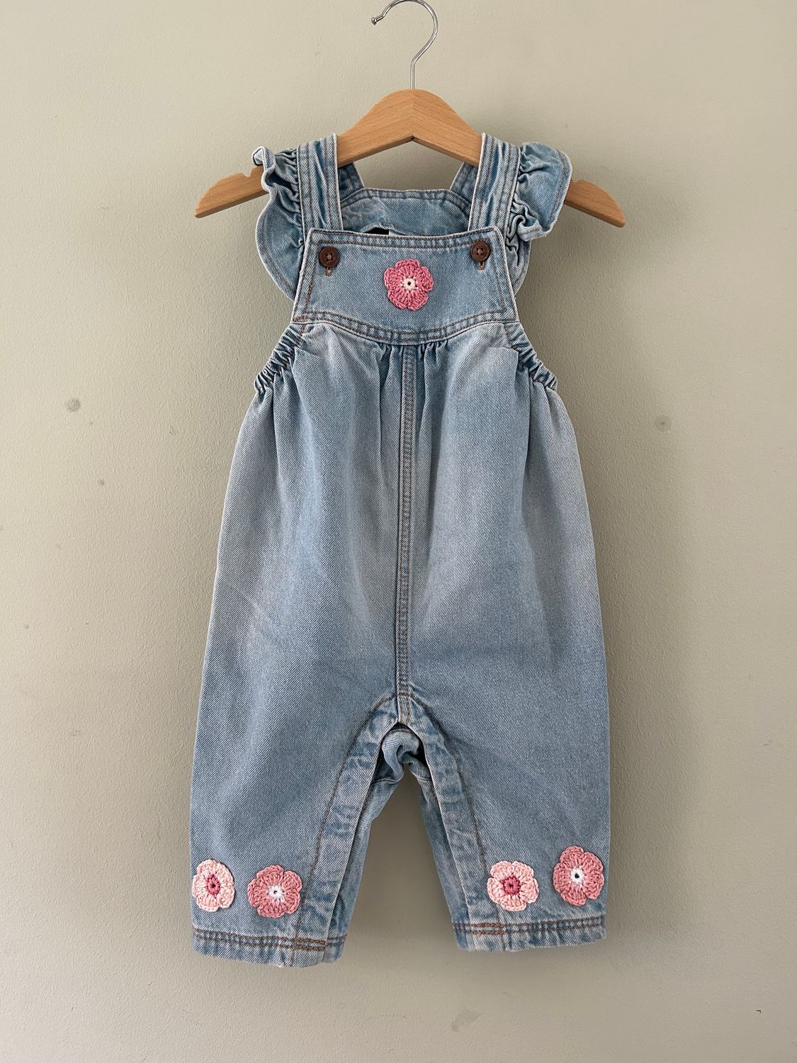 Baby tuinbroekje met gehaakte bloemetjes (rose/wit) en roezel schouderbandjes. Mt 74