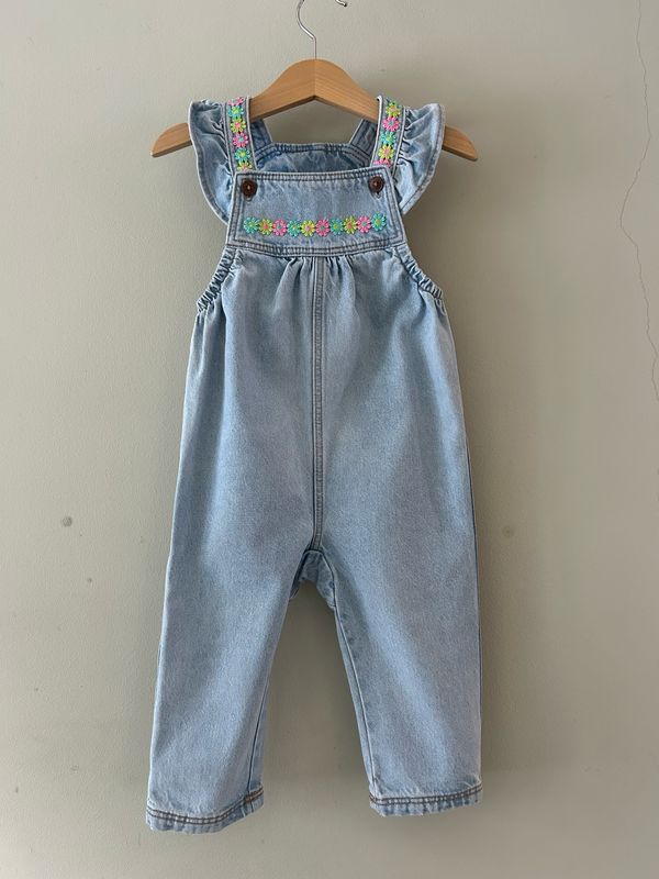 Baby tuinbroekje met bloemetjes randjes en roezel schouderbandjes. Mt 86