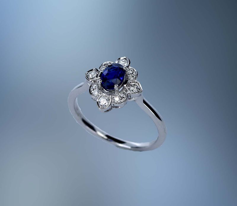 14KT WHITE GOLD DIAMOND & SAPPHIRE RING FEATURING ONE .65 CT OVAL SAPPHIRE & 12 ROUND BRILLIANT DIAMONDS TOTALING .16 CTS