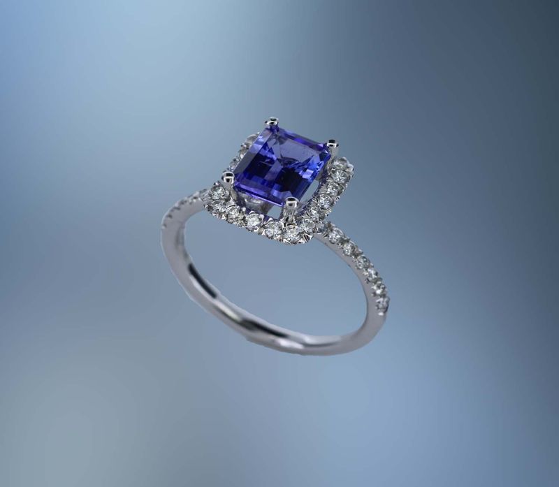 14KT WHITE GOLD TANZANITE AND DIAMOND HALO STYLE RING FEATURING  ONE 1.61 CT EMERALD CUT TANZANITE WITH 34 ROUND BRILLIANT CUT DIAMONDS TOTALING .49 CTS.