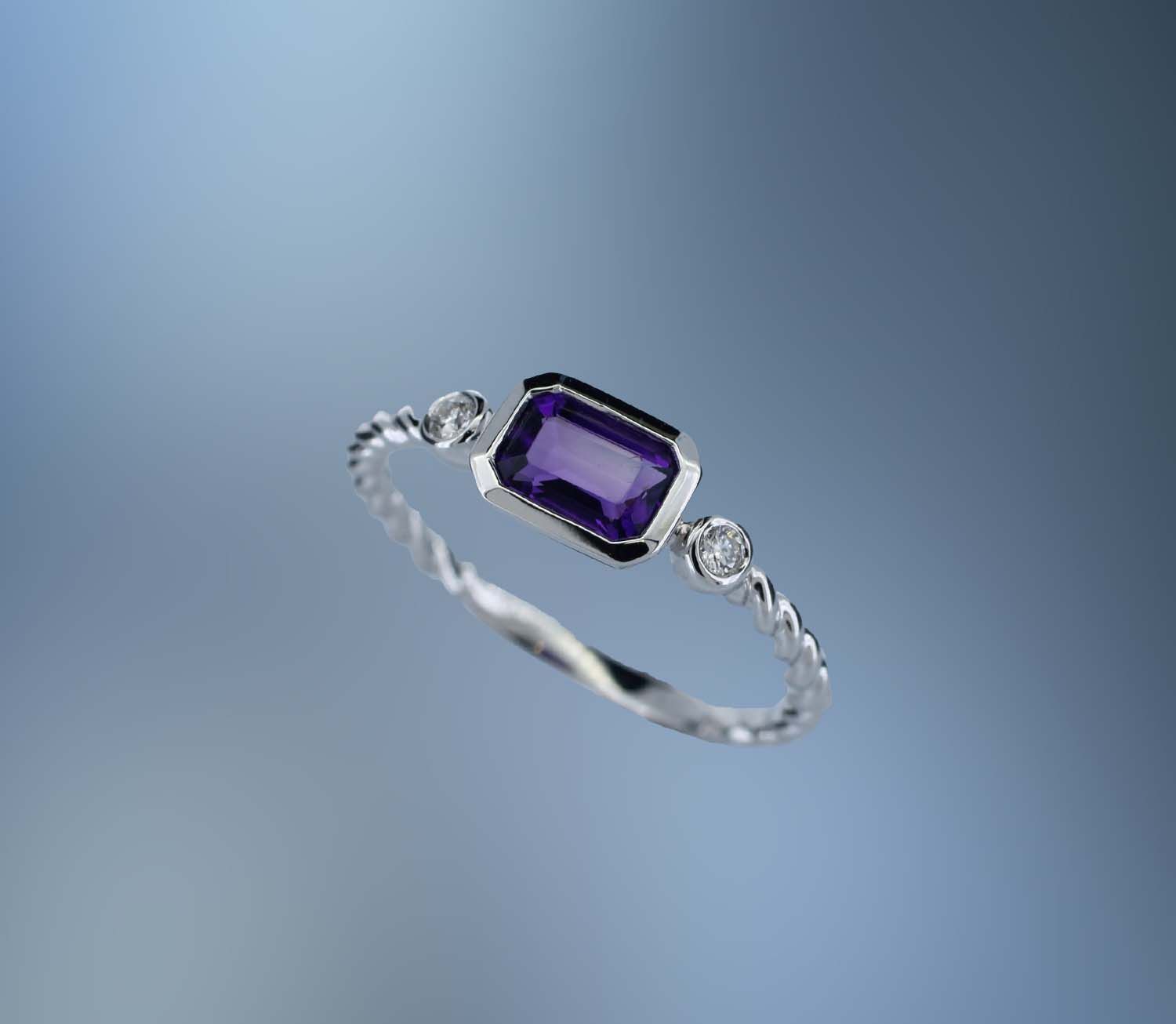 ONE 14KT WHITE GOLD LADIES AMETHYST AND DIAMOND RING CONTAINING ONE .62 CT. EMERALD CUT AMETHYST SET EAST/WEST, WITH .05 CTS OF ROUND BRILLIANT CUT DIAMONDS​ ​