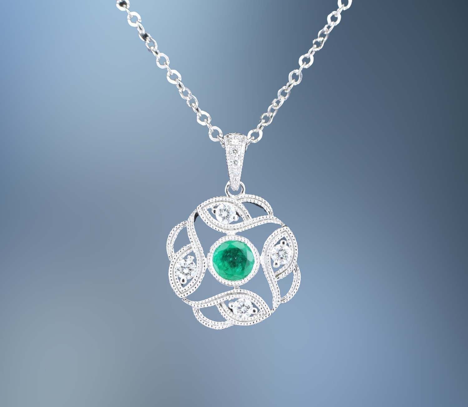 14KT WHITE GOLD EMERALD AND DIAMOND PENDANT FEATURING ONE .30 CT. ROUND BRILLIANT CUT EMERALD AND 8 ROUND BRILLIANT CUT DIAMONDS TOTALING .12 CTS. 14KT WHITE GOLD EMERALD AND DIAMOND PENDANT FEATURING ONE .30 CT. ROUND BRILLIANT CUT EMERALD AND 8 ROUND BRILLIANT CUT DIAMONDS TOTALING .12 CTS.