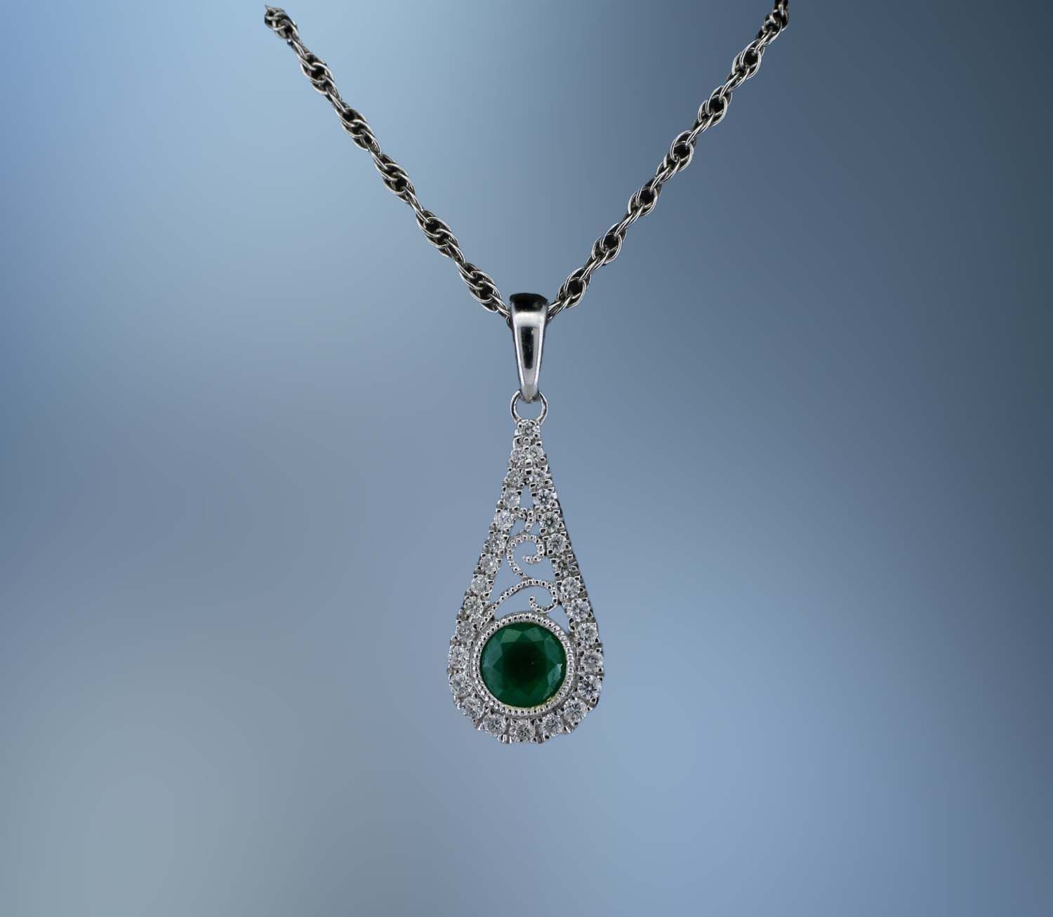 14KT WHITE GOLD LADY'S PENDANT FEATURING ONE ROUND BRILLIANT CUT EMERALD TOTALING .30 CTS AND 28 ROUND BRILLIANT CUT DIAMOND TOTALING .12 CTS 14KT WHITE GOLD LADY'S PENDANT FEATURING ONE ROUND BRILLIANT CUT EMERALD TOTALING .30 CTS AND 28 ROUND BRILLIANT CUT DIAMOND TOTALING .12 CTS