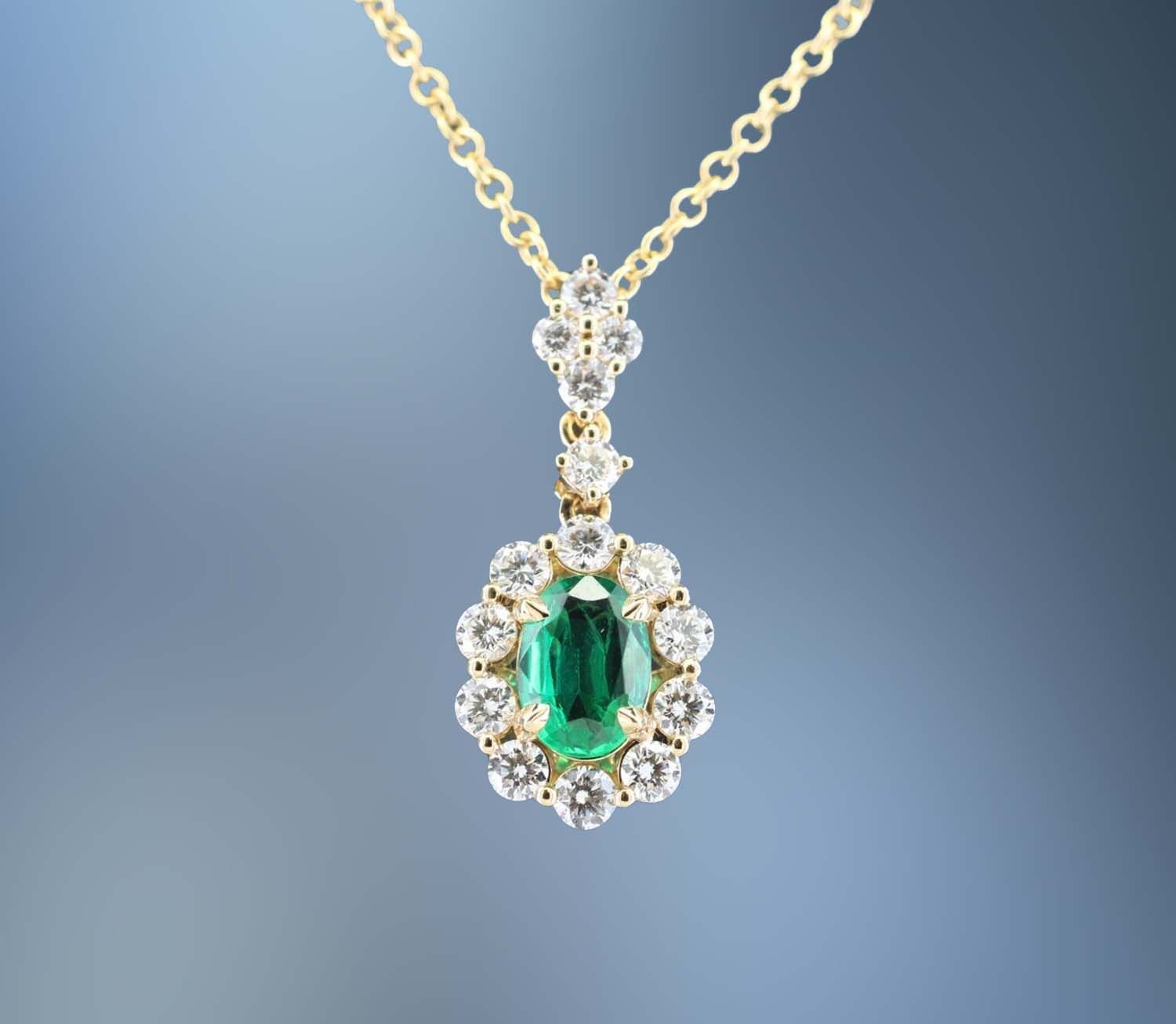 18 KARAT EMERALD AND DIAMOND PENDANT CONTAINING ONE OVAL SHAPED EMERALD WEIGHING 0.53 CARATS AND 15 ROUND BRILLIANT CUT DIAMONDS TOTALING 0.69 CARATS