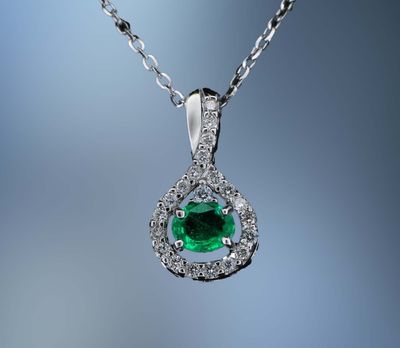 18 KT WHITE GOLD DIAMOND AND EMERALD PENDANT FEATURING 1 OVAL NATURAL EMERALD TOTALING 0.58 CTS AND 21 ROUND BRILLIANT CUT DIAMONDS TOTALING 0.26 CTS 18 KT WHITE GOLD DIAMOND AND EMERALD PENDANT FEATURING 1 OVAL NATURAL EMERALD TOTALING 0.58 CTS AND 21 ROUND BRILLIANT CUT DIAMONDS TOTALING 0.26 CTS