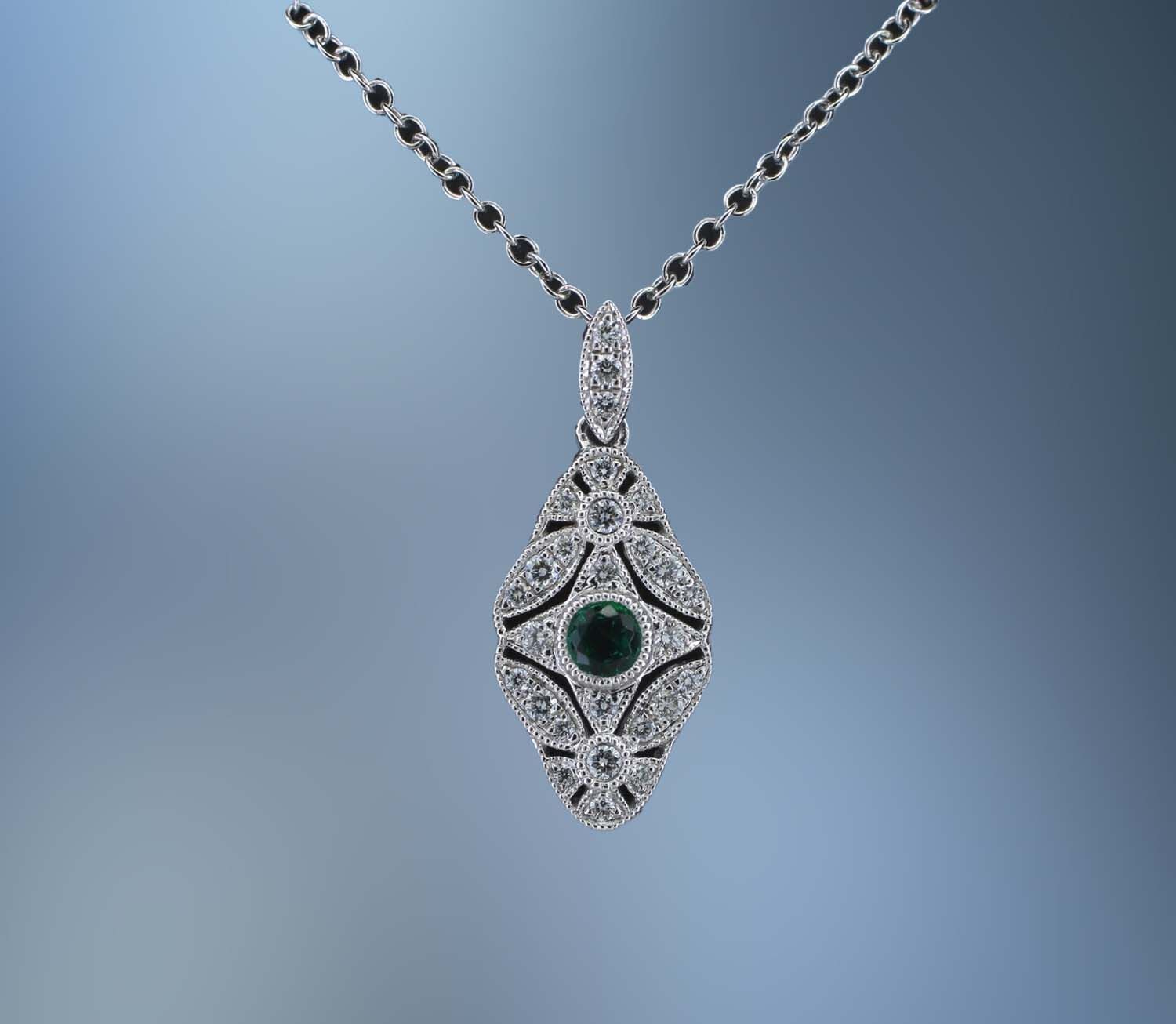 LADY'S 14KT WHITE GOLD PENDANT FEATURING 1 ROUND BRILLIANT CUT EMERALD TOTALING .14 CTS AND 27 ROUND BRILLIANT DIAMONDS TOTALING .18 CTS ON AN 18 LADY'S 14KT WHITE GOLD PENDANT FEATURING 1 ROUND BRILLIANT CUT EMERALD TOTALING .14 CTS AND 27 ROUND BRILLIANT DIAMONDS TOTALING .18 CTS ON AN 18" CHAIN