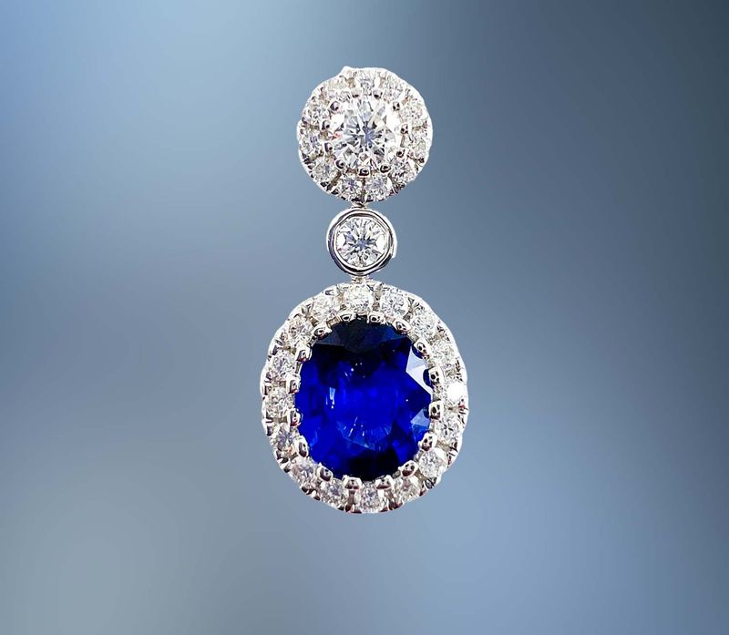 ONE 14KT WHITE GOLD PENDANT CONTAINING ONE NATURAL OVAL FACETED BLUE SAPPHIRE TOTALING .72 CTS AND 29 NATURAL ROUND BRILLIANT CUT DIAMONDS TOTALING .28 CTS