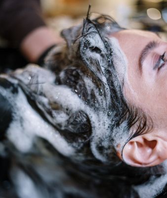 Haar van dame wordt gewassen met shampoo bij de kapper