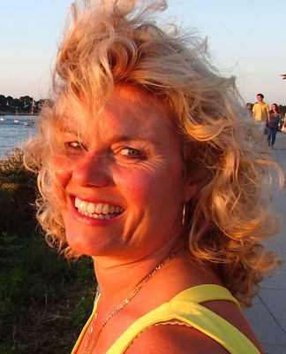 dame met krullen in de wind met de zon op haar gezicht als voorbeeld voor gebruik van stylingproducten