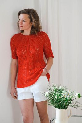 Das Modell trägt einen lässigen Sommer Lochmuster Pullover, der aus Lanamania Pearl Garn in Rot gestrickt ist.
