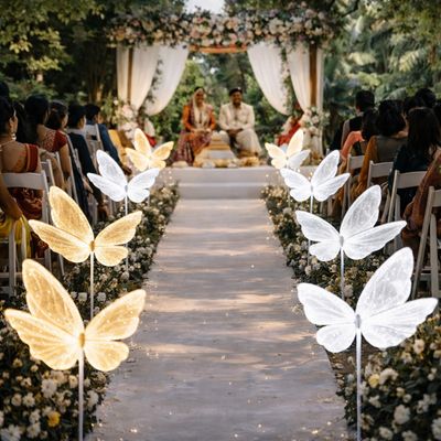 Feature butterfly lights lining an outdoor wedding aisle creating a glowing pathway for guests and ceremony setting
