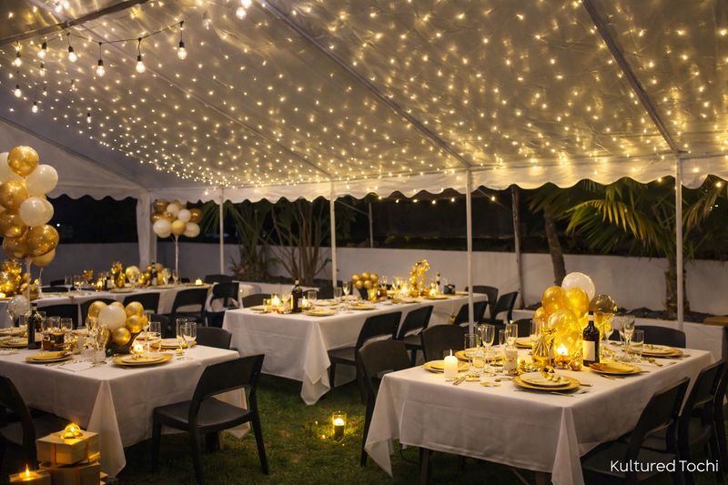 Warm white LED net lights wrapped across a marquee ceiling, creating a soft glowing canopy over a decorated outdoor dining se